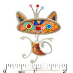Cat face pin with crown, orange and turquoise painted face, and dangling body next to ruler showing 2 in