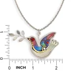 Necklace pendant next to ruler showing dove approximately 1 in high by 1.9 in wide
