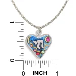 Necklace pendant next to ruler showing blue heart with Chai approximately 0.8 in square